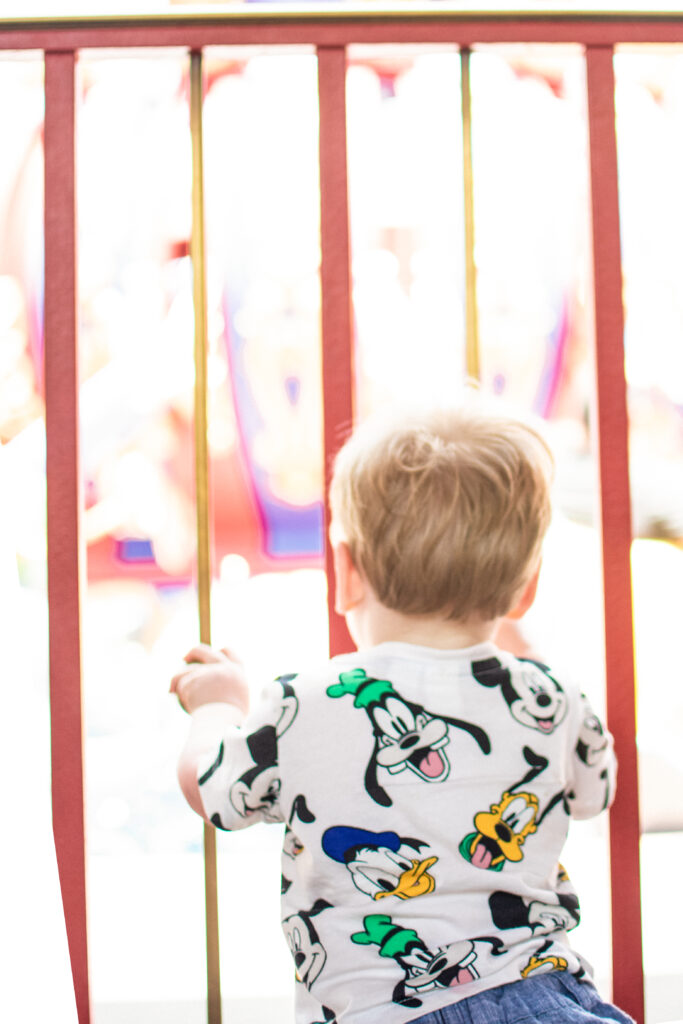 little boy looks through fence watching others board the dumbo ride at walt disney world